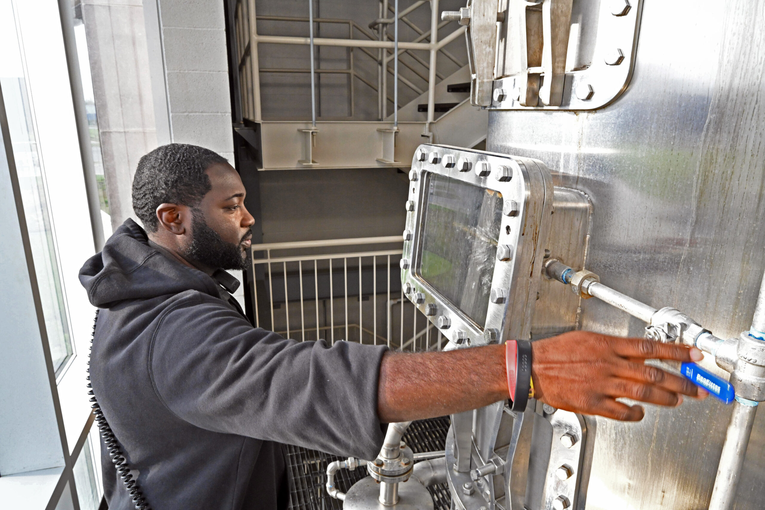 Master distiller standing in front of machinery used for contract distilling.