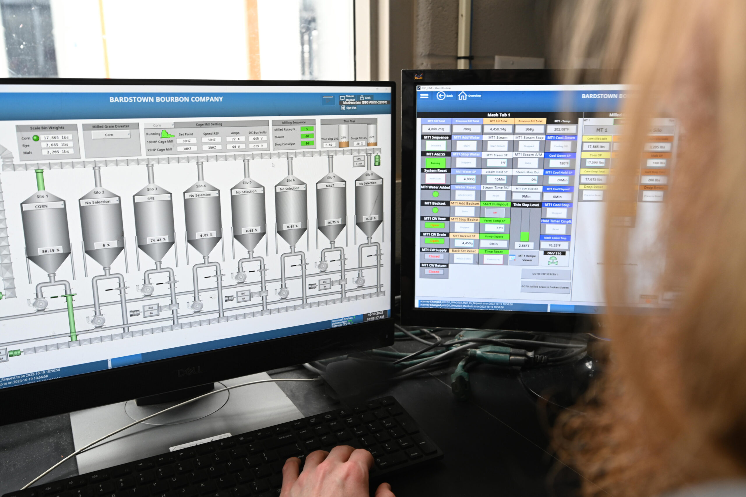 Person looking at two computer monitors during contract distilling process.