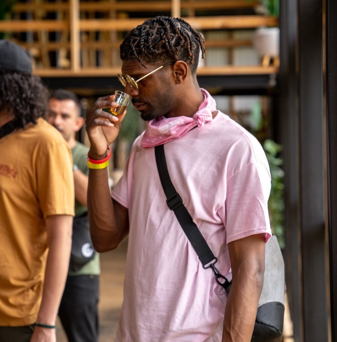 Man in pink shirt and sunglasses savoring a whiskey tasting, holding a glass from Bardstown Bourbon Company.